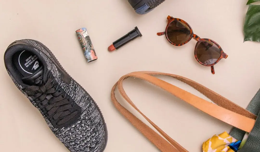 photo of bag, sneakers, and sunglasses on beige surface